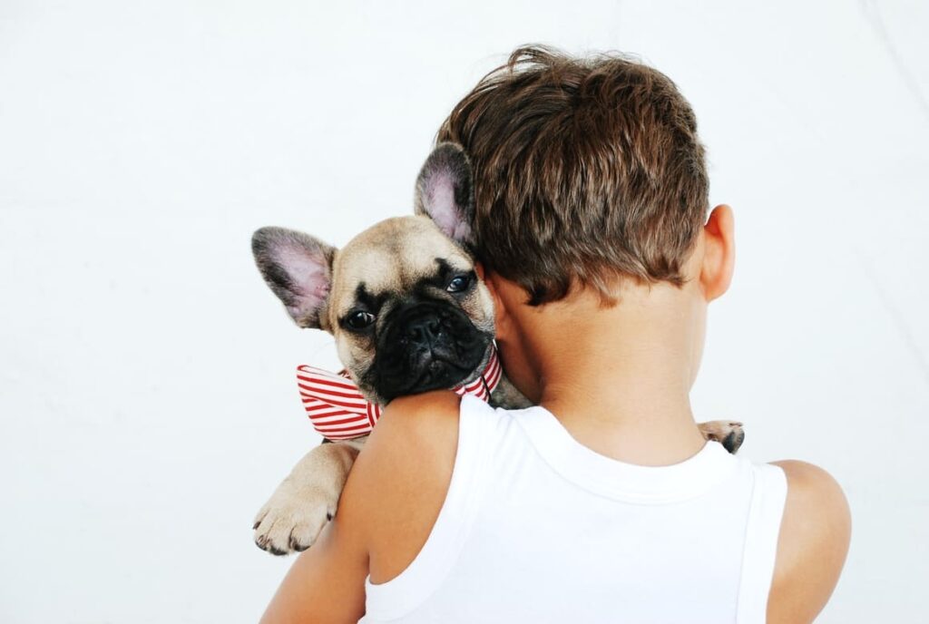 Boy holding a puppy on his shoulder trying to decide what name to call her